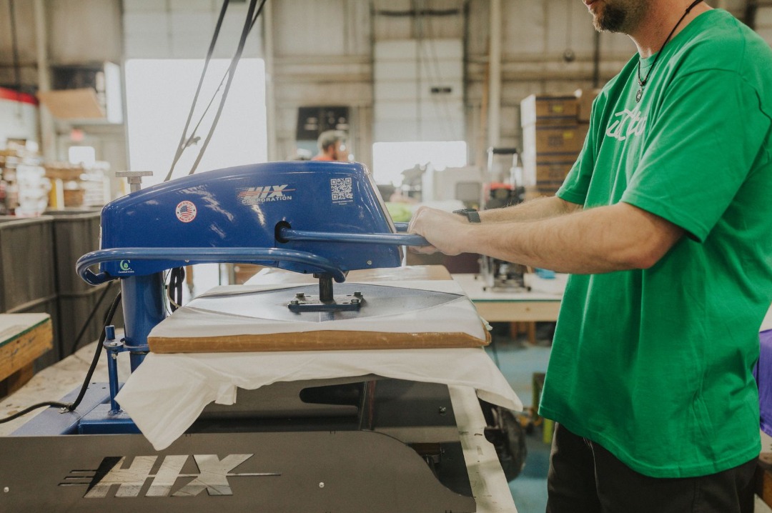BlueCotton team member Jerry heat pressing a direct to film image onto a white tshirt using our Hix heat press machine